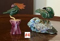 Both bird carvings displayed side by side on wooden surface showing relative size and base materials