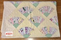 Quilt laid flat showing full array of fan blocks on pale yellow background