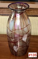 Front view of iridescent glass vase showing red webbing pattern and white heart motifs with cobalt blue rim