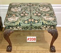 Front view of entire footstool showing upholstery pattern and carved legs