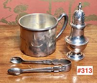 Overall view of mug, sugar tongs, and shaker on wooden surface