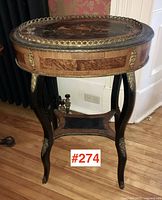 Front view of oval table showing overall structure, curved legs and marquetry top.