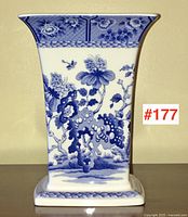 Front view of square-based porcelain vase with blue floral motif beneath flared rim