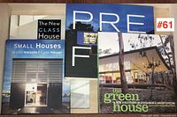 Four architecture reference books arranged on a light wood surface. Covers visible include titles and photographic images of modern houses.