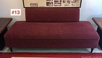 Front view of red upholstered sofa/daybed with poster overhead