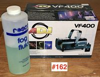 Bottle of Rosco fog fluid next to the boxed ADJ VF400 fog machine, displaying branding and model.