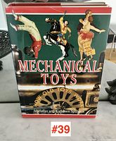 Front cover of the hardcover book labeled 'Mechanical Toys' with images of mechanical toy figures and gears.