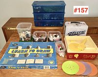Wide shot of all items on table including Fisher Price player, toy figures, game and lunchbox