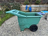 Side view of the green utility lawn cart displaying its two black wheels and handle, showing lightweight and functional design for garden or yard use.