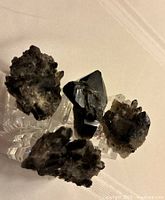 Four varied dark smoky and black crystal geode napkin rings displayed on white surface.