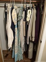 Overview of hanging clothes including sweaters, dresses, and cardigans with mix of pastels, florals and neutrals.