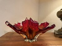 Side profile of Murano glass bowl showing maple leaf shape and color gradient from red to amber to clear glass base.