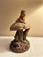 Gnomes sitting and standing around a textured mushroom with a seated gnome on top. The figures are finely detailed and painted in natural earthy tones.