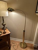 Full view of floor lamp lit, showing base, column, curved arm, and glowing shade