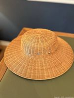 Top-down view of the wicker straw pith helmet hat showing the woven texture and round crown shape.