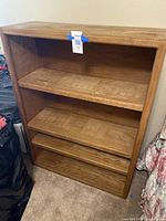 Full view of the oak wood bookshelf showing the four shelves and overall condition with some visible wear.