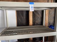 Top-down view of one of the plastic shelving levels showing grid design and metal frame context