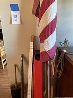 Photo showing a 72-inch red and white striped flag attached to a metal pole with 1/2 eagle finial, alongside various wooden and metal sticks, including a cane and tripod.