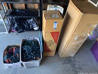 Overall view of boxed artificial Christmas trees and string lights stored in bins in garage or storage area.