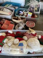 Photo showing multiple storage bins filled with Christmas decorations including stuffed snowmen, boxes of ornaments, and other holiday decor items.