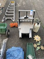 Overview of garden tools and accessories including lawn mower, ladder, cart, sprayer, rope, tarps, buckets, and garden decorations.