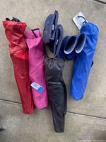 Top-down view of four folded outdoor chairs in red, pink, black, and blue carrying bags next to two blue cushioned seat pads.