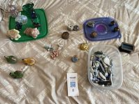 Wide view of all figurines and small decorative pieces laid out on a bed, showing variety in shapes, colors, and finishes.