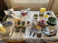 Top down view of mixed dinnerware items on table showing plates, cups, bowls, glassware, spoons, and trays in a variety of colors and styles.