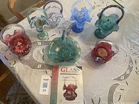 Group view of four hand-painted glass baskets in purple, blue, red, and green arranged on table