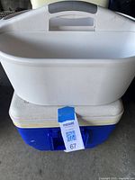 View of white Sterilite caddy sitting on top of the blue and white Igloo cooler, showing the handle and rounded shape of the caddy and cooler details.