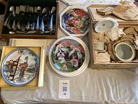 Top view of multiple decorative plates and boxed silverware set on table