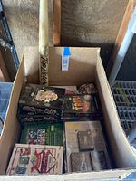 Photo of open cardboard box containing multiple unopened sports trading card boxes and a wooden baseball bat