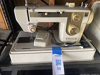 Front and side view of Nelco SZ-217 electric sewing machine showing controls, foot pedal, and power cord on the base.