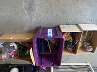 Plastic storage tub containing three open cardboard boxes and one sealed plastic bag of troll dolls