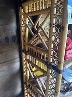 Close-up detail of bamboo and rattan construction showing cross braces and weaving pattern on shelving unit's side.