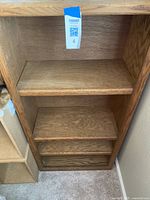 Front view of traditional oak wood bookshelf showing three shelves and natural wood grain texture.
