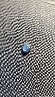 Oval blue star sapphire on textured black surface under flash light