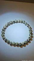 Front view of natural dalmatian jasper bead bracelet on a flat surface showing bead color and spots