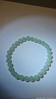 Close-up photo of the natural green aventurine bracelet laid flat with beads visible.