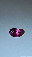 Close-up frontal photo of the oval cut hot pink topaz gemstone showing its color, cut, and clarity.