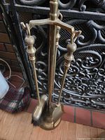 Full view of brass tool set on stand in front of fireplace