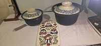 Full set showing two blue pots with floral lids and ceramic trivet
