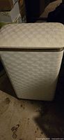 Front view of laundry hamper showing white textured vinyl exterior and gold trim