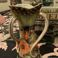 Front angle of antique three-handled porcelain vase showing floral hand-painted design and gold gilding wear.