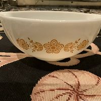Front view of bowl showing golden floral design and side handle.