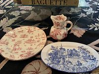 Three pieces shown together: red and blue patterned plates and a red patterned Masons jug