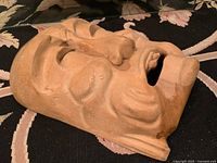 Side view of the large wooden mask showing contours and carved facial features.