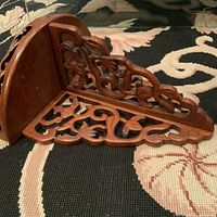 Side angled view of the vintage Asian rosewood carved wall shelf showing intricate carved vine and floral design and semi-circular shelf top.