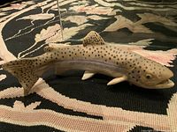 Side view of vintage Japanese hand-made pottery fish sculpture on patterned fabric background showing detailed fins and speckled pattern.