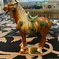 Side view of the vintage Tang Sancai pottery war-horse statue showing tri-color glaze and detailed saddle.